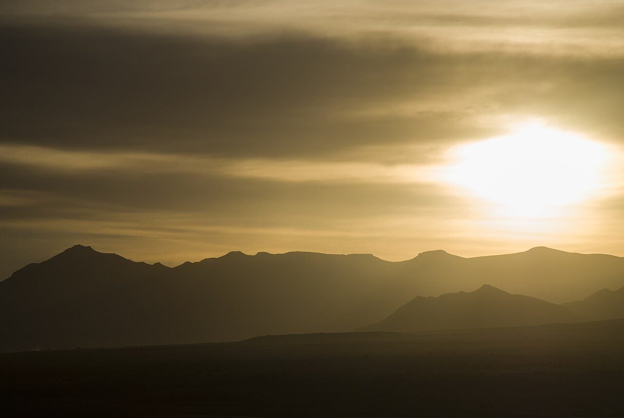 Soft golden morning light over the Erg Chebbi sand dunes near Merzouga with a lone camel train on the crest