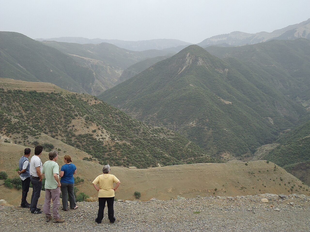 Hiker on a mule track above terraced fields and an earth-built Berber village in the High Atlas near Imlil