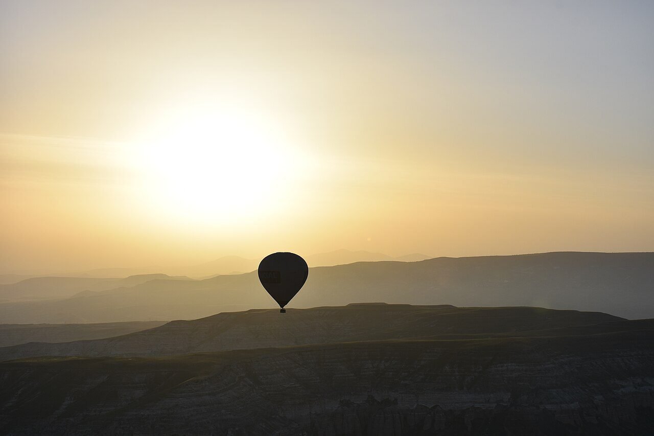 Hot air balloons floating at sunrise over the plains near Marrakech with the snow-capped High Atlas in the distance
