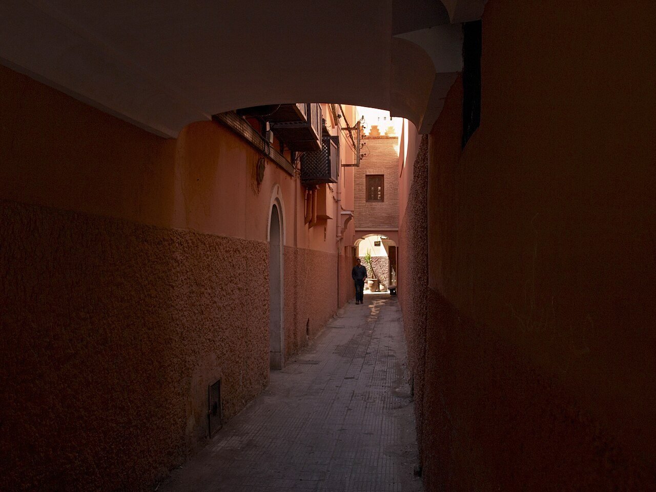 Busy lane in the Marrakech medina souks with shoppers and market stalls