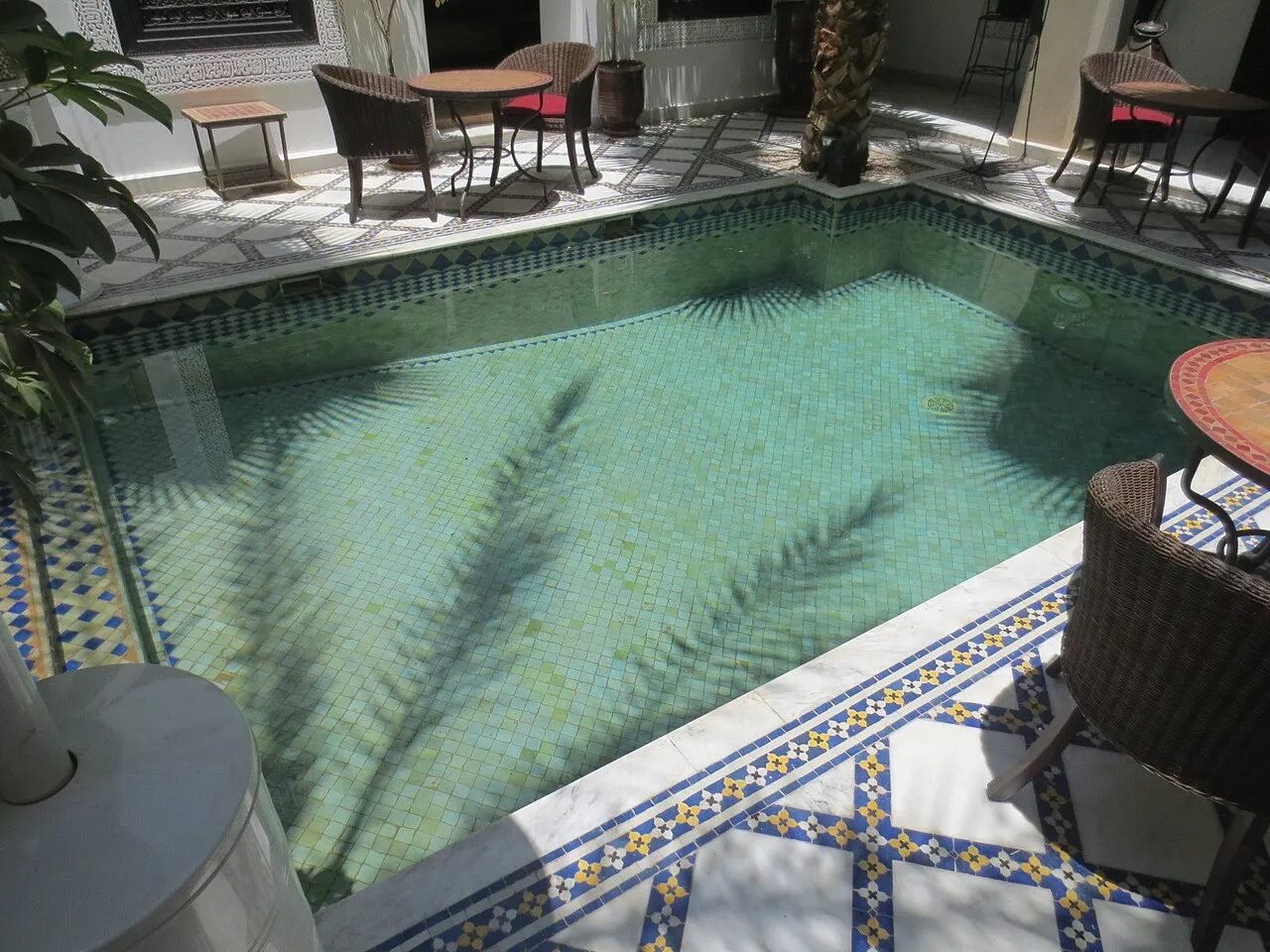 Courtyard of a Moroccan riad with a fountain, orange trees and arcades
