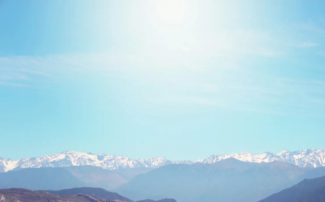 Snow-capped High Atlas peaks seen beyond palm trees in Marrakech in winter